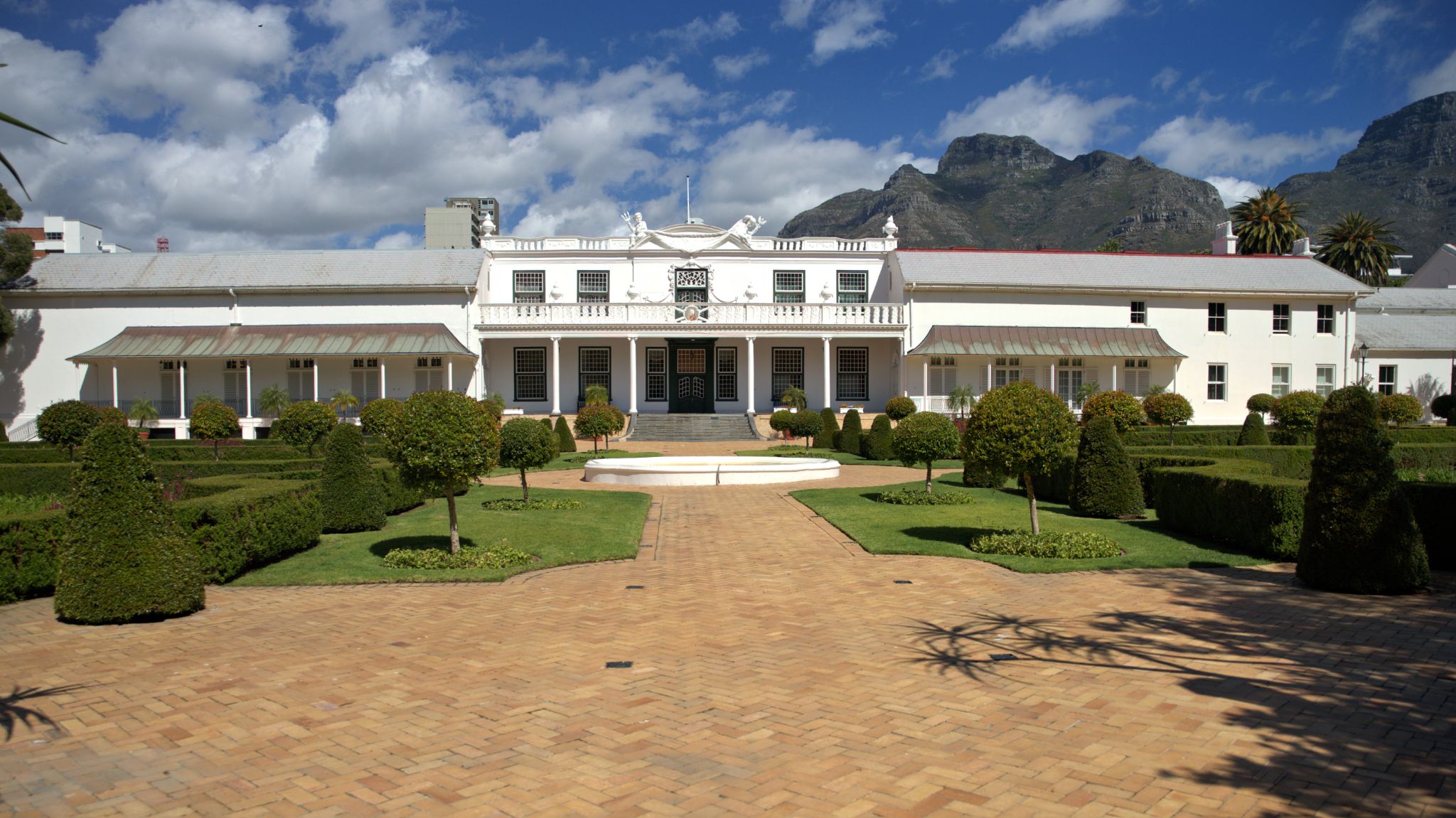 Das Gebäude im Bild ist das Tuynhuys in Kapstadt, die offizielle Residenz des Präsidenten, ursprünglich 1674 von der Niederländischen Ostindien-Kompanie als Gartenhaus gebaut.